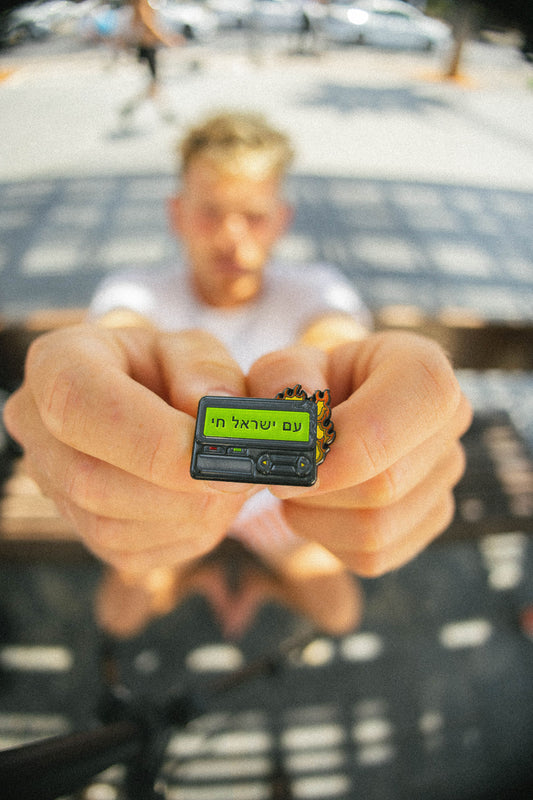 Person holding a small beeper pin with text on it, blurred background