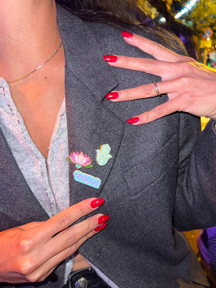 Person wearing a gray blazer with colorful pins, holding their blazer.
