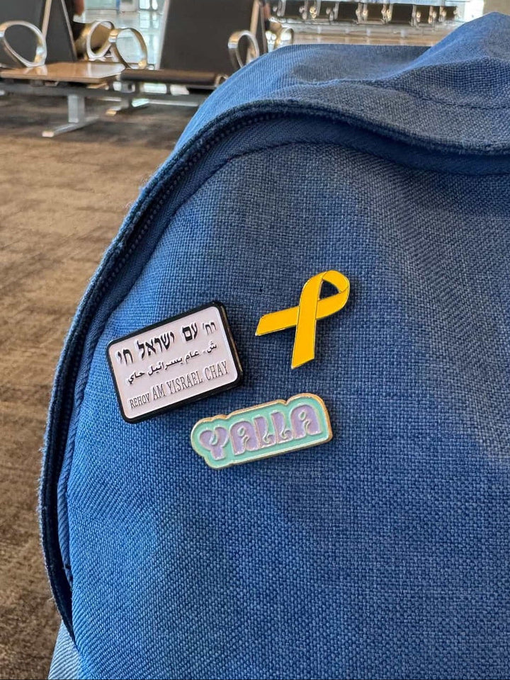 Blue backpack with patches including a yellow ribbon and a name tag in an indoor setting