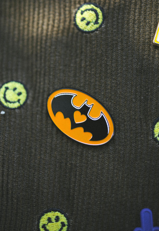 Black with orange bat logo and green smiley faces on a textured background