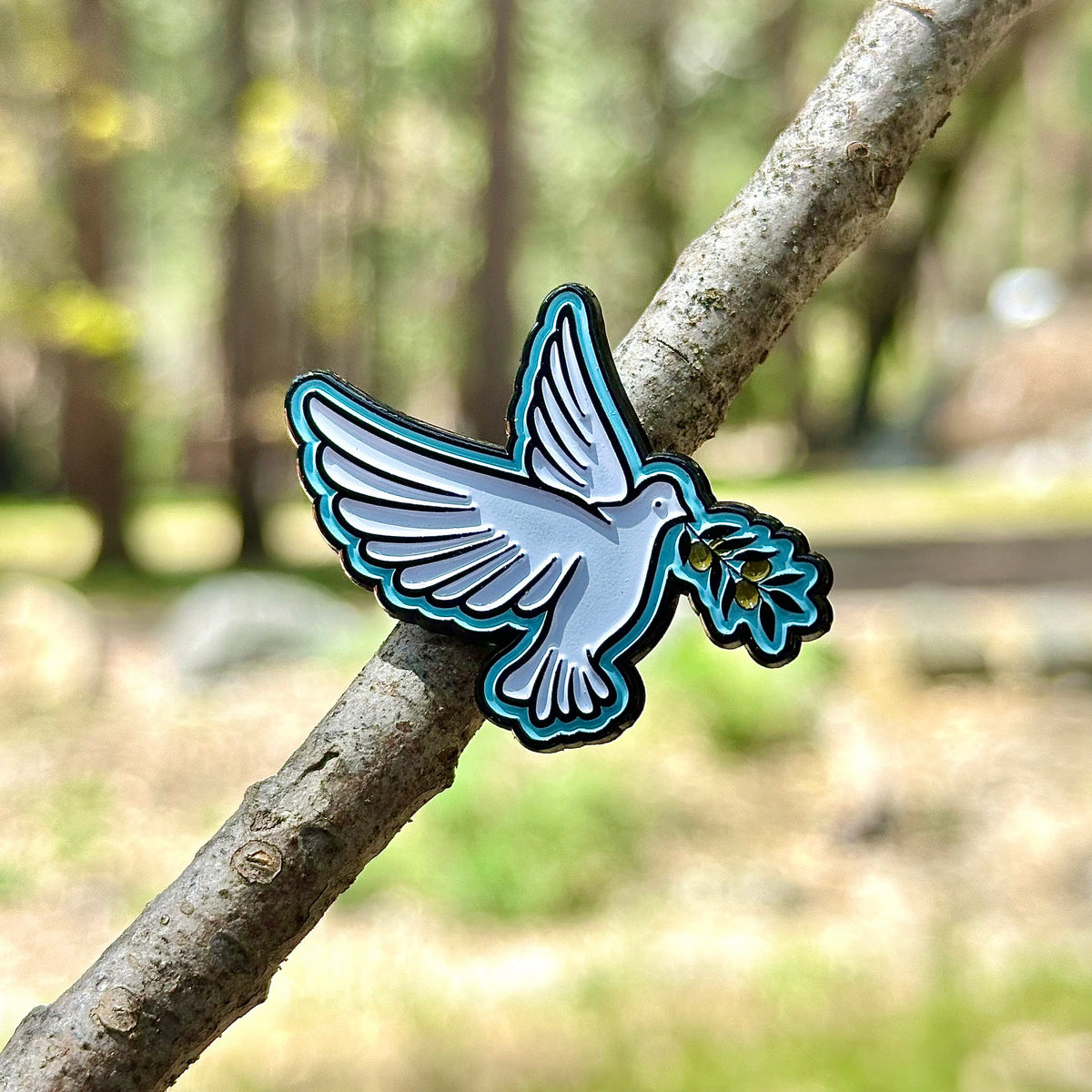 Decorative pin of a bird with a flower on a branch in a natural setting