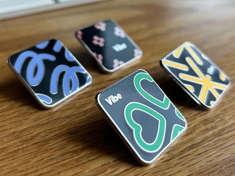 Four decorative pins with unique designs on a wooden surface
