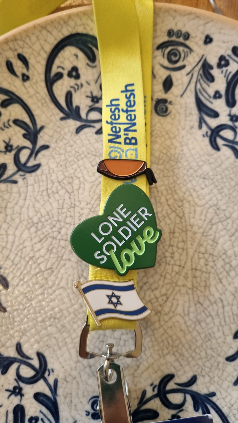 Lanyard with a green heart-shaped tag and Israeli flag design on a textured surface.