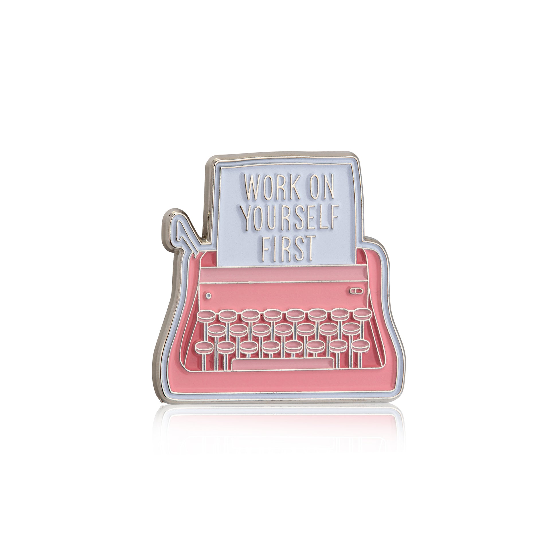 Enamel pin shaped like a typewriter with 'Work on Yourself First' text on a white background
